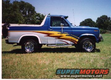 Blue 1980-1986 Ford Bronco with flame graphics and spare tire on rear