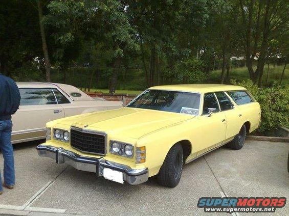 Yellow station wagon with chrome bumper and black grille, parked next to a tan sedan