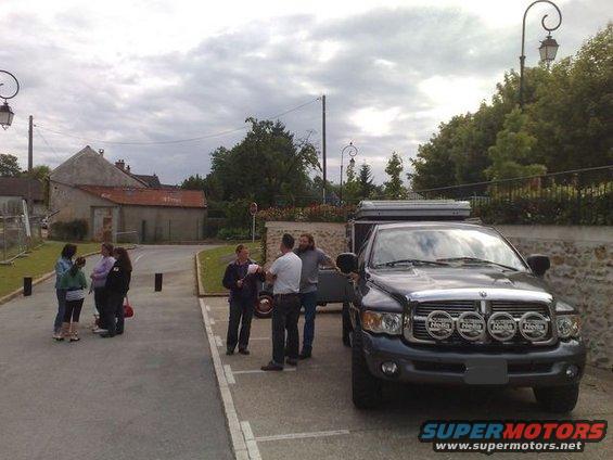 Dark gray pickup truck with camper shell and four auxiliary lights on front