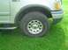 2001 Ford Expedition - Front wheel and fender of a 2001 Ford Expedition parked on grass.