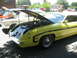 1972 Ford Ranchero - A yellow 1970s coupe is parked with its hood open, alongside other vehicles.