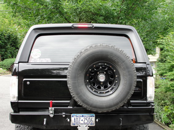 Rear view of a black 1995 Ford Bronco with a spare tire mounted on the tailgate and a New York license plate