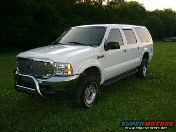 White 2000 Ford Excursion with chrome grille and bull bar parked on grass