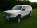 2000 Ford Excursion - This 2000 Ford Excursion is shown in a three-quarter front view, parked on a grassy field with trees in the background.