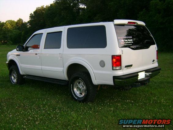 White 2000 Ford Excursion parked on grass, rear 3/4 view