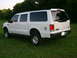 2000 Ford Excursion - Rear 3/4 view of a white 2000 Ford Excursion parked on a grassy lawn with trees in the background.