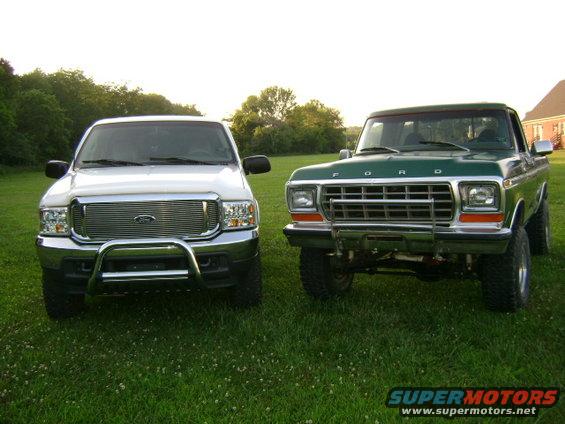 White Ford Excursion and green Ford truck parked on grass