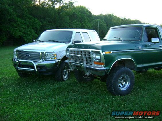 White 2000 Ford Excursion parked next to a green Ford Bronco