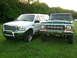 2000 Ford Excursion - Two Ford trucks, a white Excursion and a green F-Series, are parked on a grassy lawn with trees in the background.