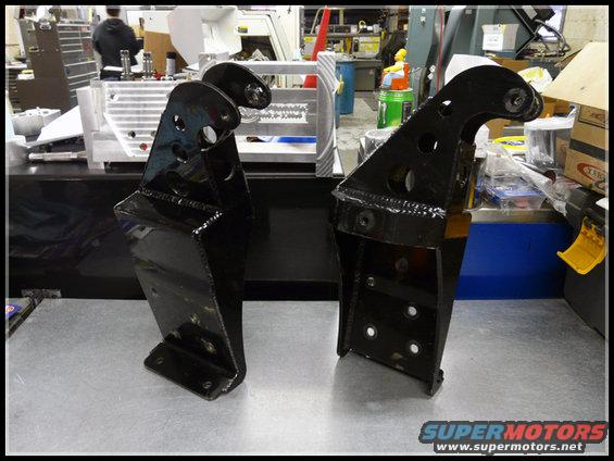Two black metal brackets on a workbench