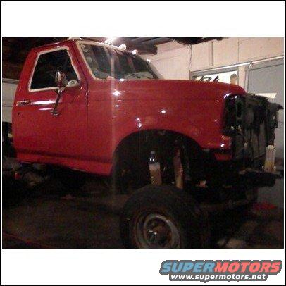 Red pickup truck, likely 1992-1997 Ford F-Series, in a garage with front end disassembled