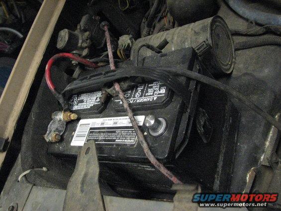Battery was relocated to the passenger side, opposite of where it should be, and is held in place with a bungee cord.