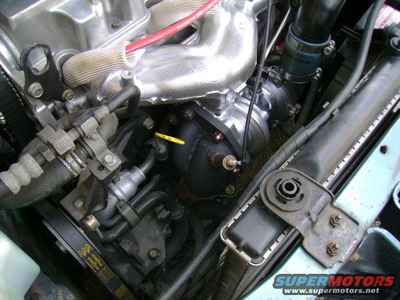 Engine bay shot showing a turbocharger, exhaust manifold, and radiator. Some hoses and belts are visible