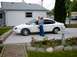 1997 Ford Taurus - A woman and child stand beside a white sedan in front of a house.