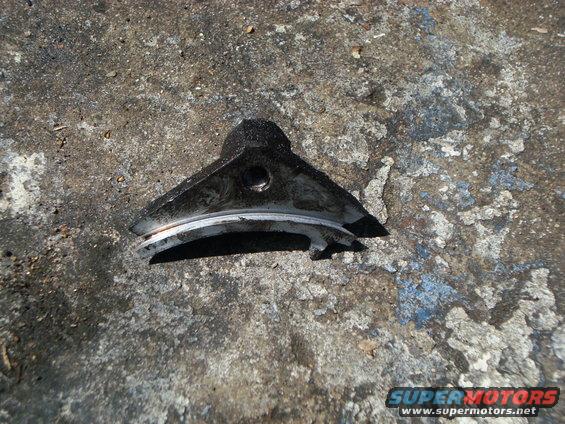 Black metal part with a silver ring, resting on concrete
