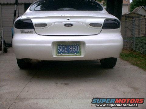 Rear view of a white 1997 Ford Taurus with a blue license plate that reads SCE 860