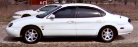 White 1997 Ford Taurus sedan, side view, parked next to another car