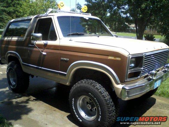 Brown and tan Ford Bronco with smiley face balloons on the roof rack