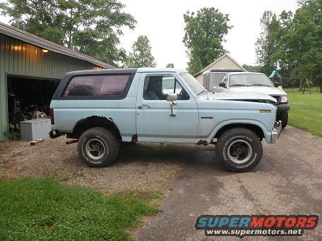 Light blue 1985 Ford Bronco side view, parked by a garage