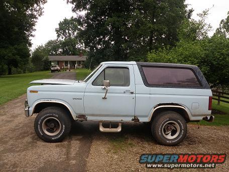 1985 Ford Bronco parked on gravel driveway with a house in the background
