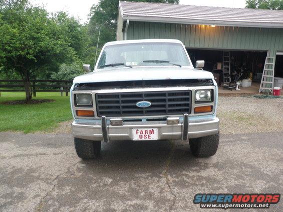 Front view of a light blue Ford F-Series truck with hood open. It has a chrome bumper and a 'FARM USE' plate