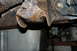 1995 Ford Bronco - Undercarriage view of heavily rusted metal frame components, indicating significant corrosion.