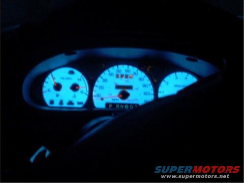 dashboard gauges with blue glow, shows speed, RPM, and gear selection
