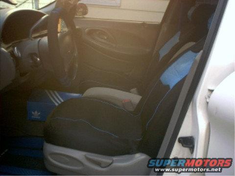 Car interior with black seat covers and blue accents, dashboard, steering wheel, and a shoe box on the floor