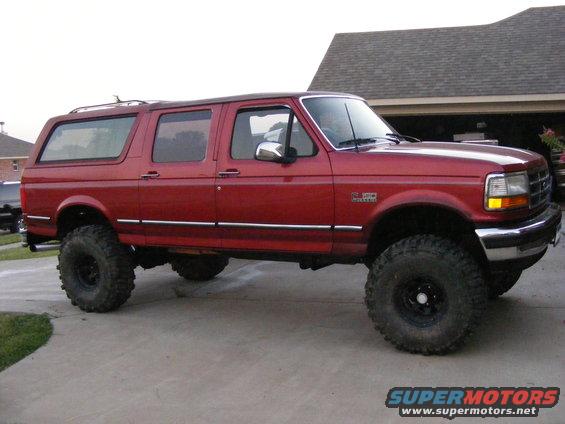 Red extended cab SUV with large tires parked on a driveway