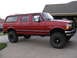1993 Ford C-150 (Centurion Conversions) - This red extended cab SUV features large off-road tires and a lifted suspension, suggesting it is modified for off-road use.
