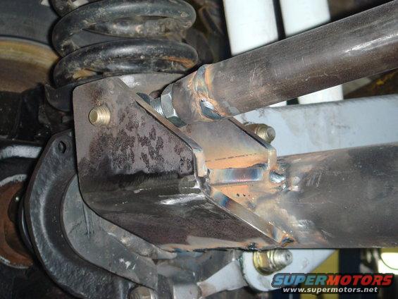 Custom fabricated suspension bracket welded to a metal tube, with a coil spring visible above