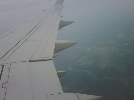 Airplane wing seen from window, with landscape below