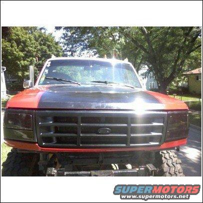 Red and black Ford F-Series truck front view, lifted with large tires. Grille is black with Ford emblem