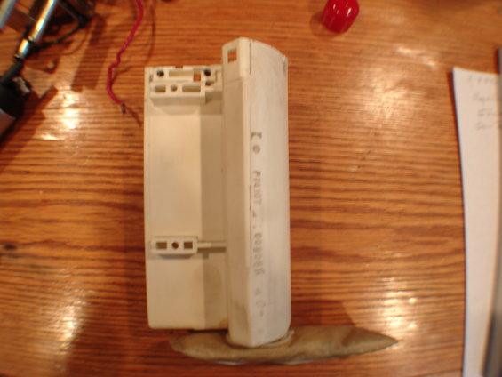 White plastic fuel pump module with a filter sock attached, resting on a wooden surface. Part number 'F4307-00068' is visible