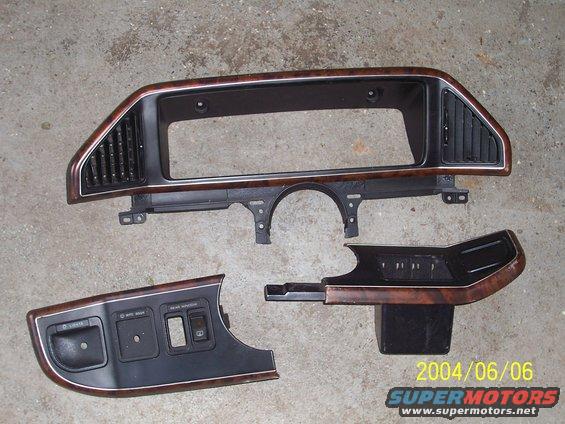 Dashboard trim pieces with wood grain accents, including a main dash bezel and a lower console section with switches