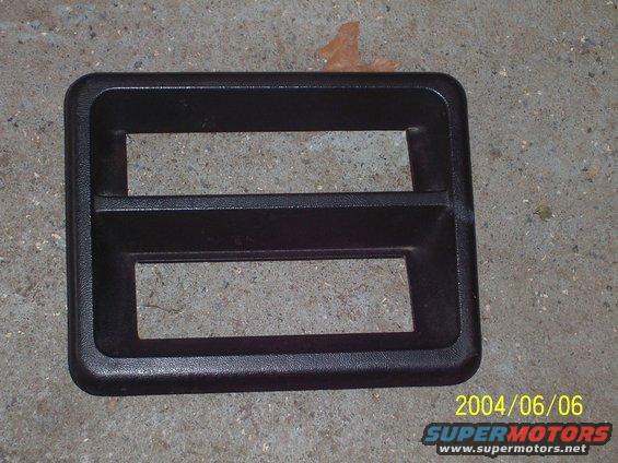 black plastic trim with two rectangular openings, possibly for gauges or switches, on a concrete surface
