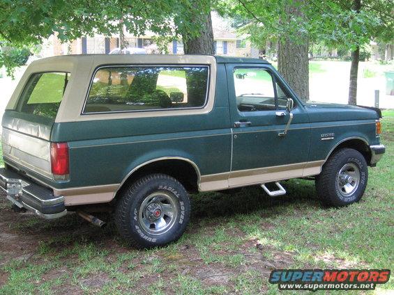 Green and tan 1989 Ford Bronco parked on grass under trees