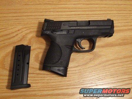 Black semi-automatic pistol with extended magazine on wooden surface