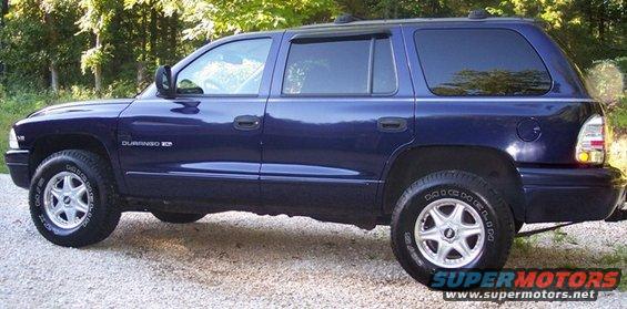 Side view of a dark blue SUV with tinted windows and silver rims. The badge on the door says 'DURANGO XD'