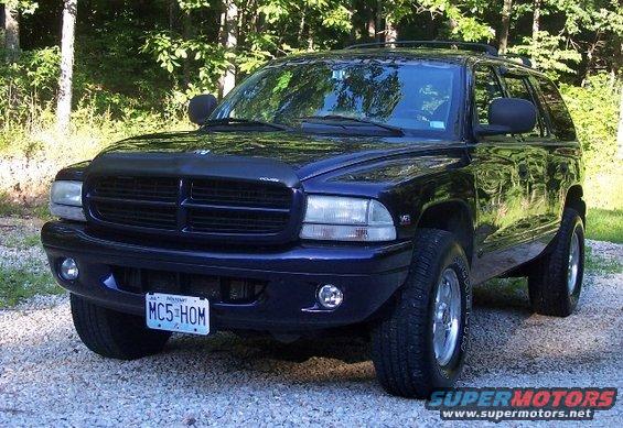 Dark blue SUV parked on gravel, front 3/4 view. Hood protector installed