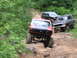 1994 Ford F-250 - Several off-road vehicles navigate a challenging dirt path in a wooded area.
