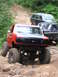 1994 Ford F-250 - A red 1994 Ford F-250 navigates a challenging off-road course with other vehicles in the background.