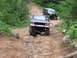 1994 Ford F-250 - Two trucks tackle a challenging off-road course with steep inclines and large rocks.