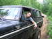 1994 Ford F-250 - A man naps in a dirty black Ford Bronco Ranger as another vehicle drives ahead on a wooded trail.