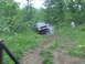 1994 Ford F-250 - A truck is stuck on a wooded trail, with smoke or steam coming from the front wheel area.