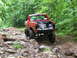 1994 Ford F-250 - Red 1994 Ford F-250 navigating a rocky off-road path through a forest.
