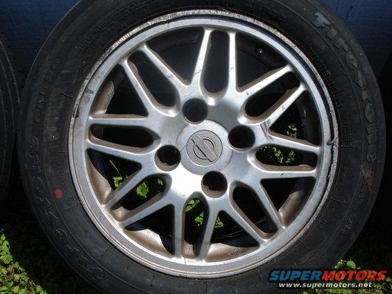 Close-up of a Nissan alloy wheel with a Firestone tire. The wheel has a Nissan logo in the center