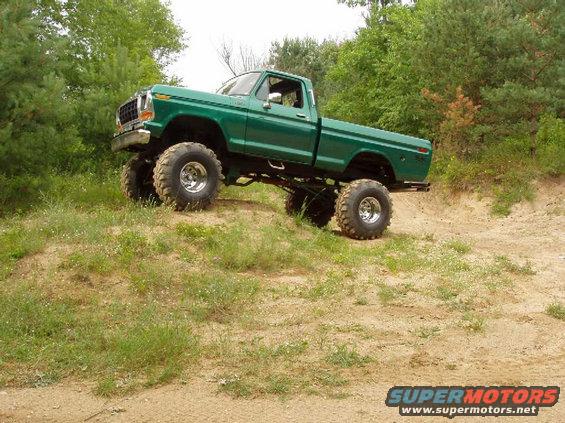 Green 1979 Ford F-100 pickup truck with large tires on a dirt hill