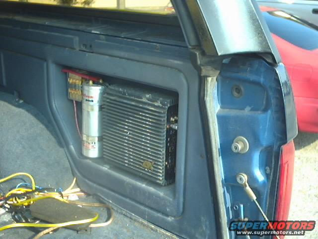 Blue vehicle interior with aftermarket car stereo amplifier and capacitor mounted on the side panel