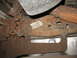 1995 Ford C-350 (Centurion Conversions) - The underside of a vehicle shows significant rust on the frame and suspension parts, with a visible label.